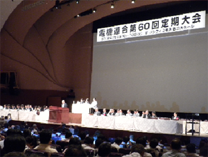 写真・檀上のようす遠景、有野委員長あいさつ